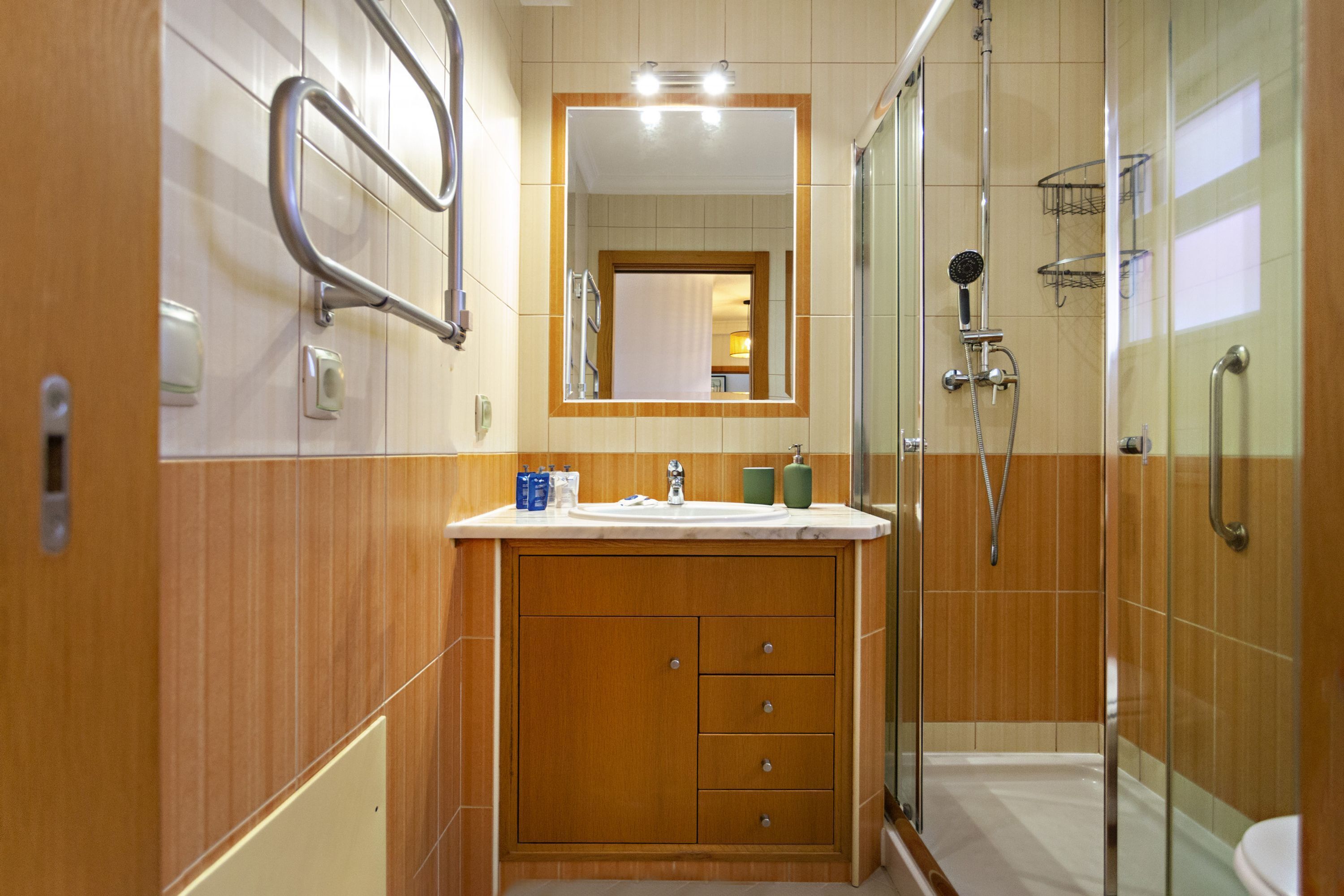 A modern bathroom with a wooden vanity, a glass shower enclosure, and a mirror above the sink.