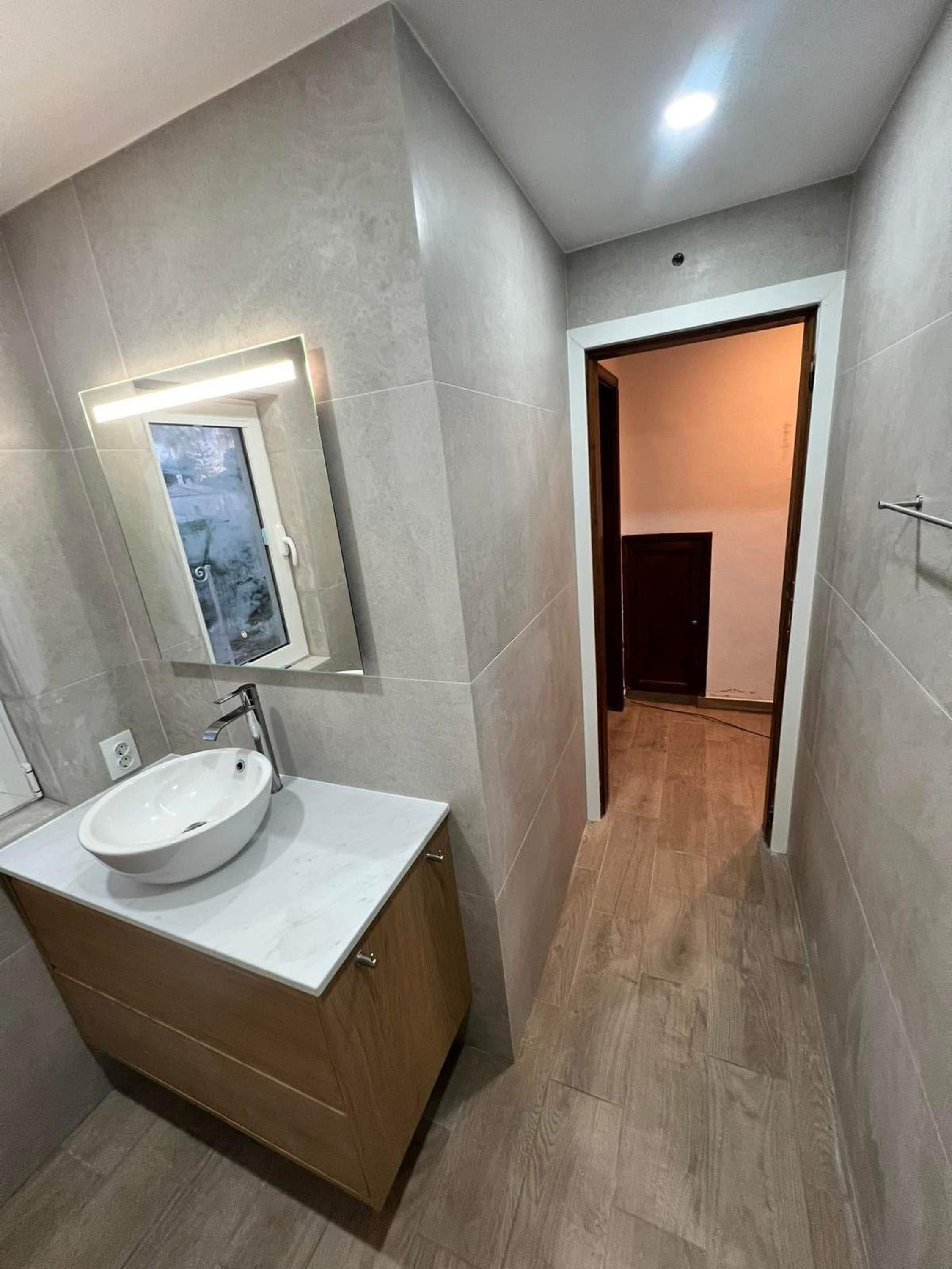 Une salle de bain moderne avec un grand lavabo, un miroir et un meuble-lavabo en bois.