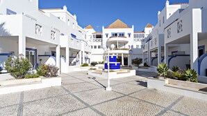 A courtyard with white buildings, a central blue structure, and cobblestone flooring. - QV 20 - Saltwater Apartment - Quinta Velha (Tavira)