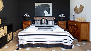 A bedroom with a large bed, two bedside tables, a wooden dresser, and a wall-mounted artwork of a horse. - QV 210 - Black White Apartment - Quinta Velha (Tavira)