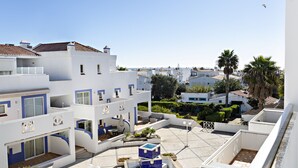 A residential area with white buildings, a pool, and palm trees. - QV 210 - Black White Apartment - Quinta Velha (Tavira)