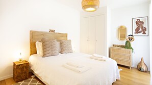 Une chambre à coucher bien rangée, avec un lit, une table de chevet et un luminaire suspendu.