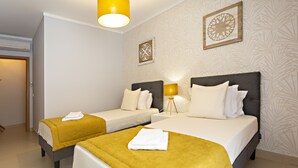 A hotel room with two beds, a bedside lamp, and a wall-mounted air conditioner.