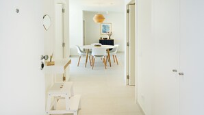 A modern, well-lit hallway leading to a dining area with a round table and white chairs. - Casas do Forte BE in Tavira (Tavira)