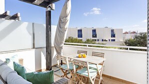 A balcony with a table and chairs, a sofa, and a pergola. - Formosa Bay - Cabanas Bay (Tavira)