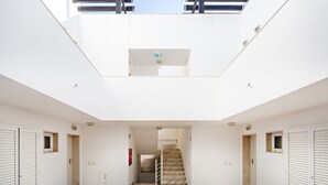 A spacious, well-lit interior with a central staircase, white walls, and a skylight. - Formosa Bay - Cabanas Bay (Tavira)