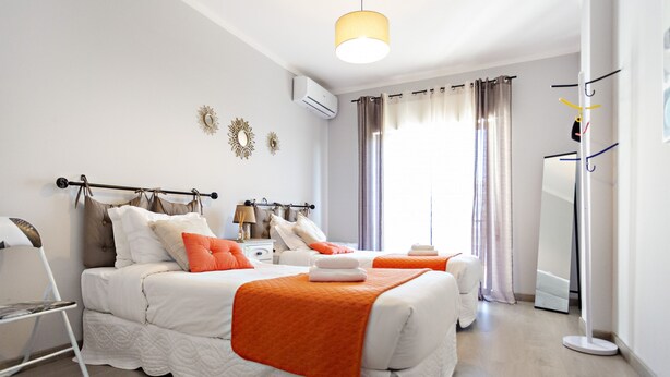 Una camera d'albergo moderna con due letti, un grande specchio e un armadio.