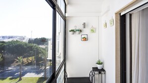 Un balcone con vista sulla città, un tavolino con una pianta in vaso e decorazioni a parete.