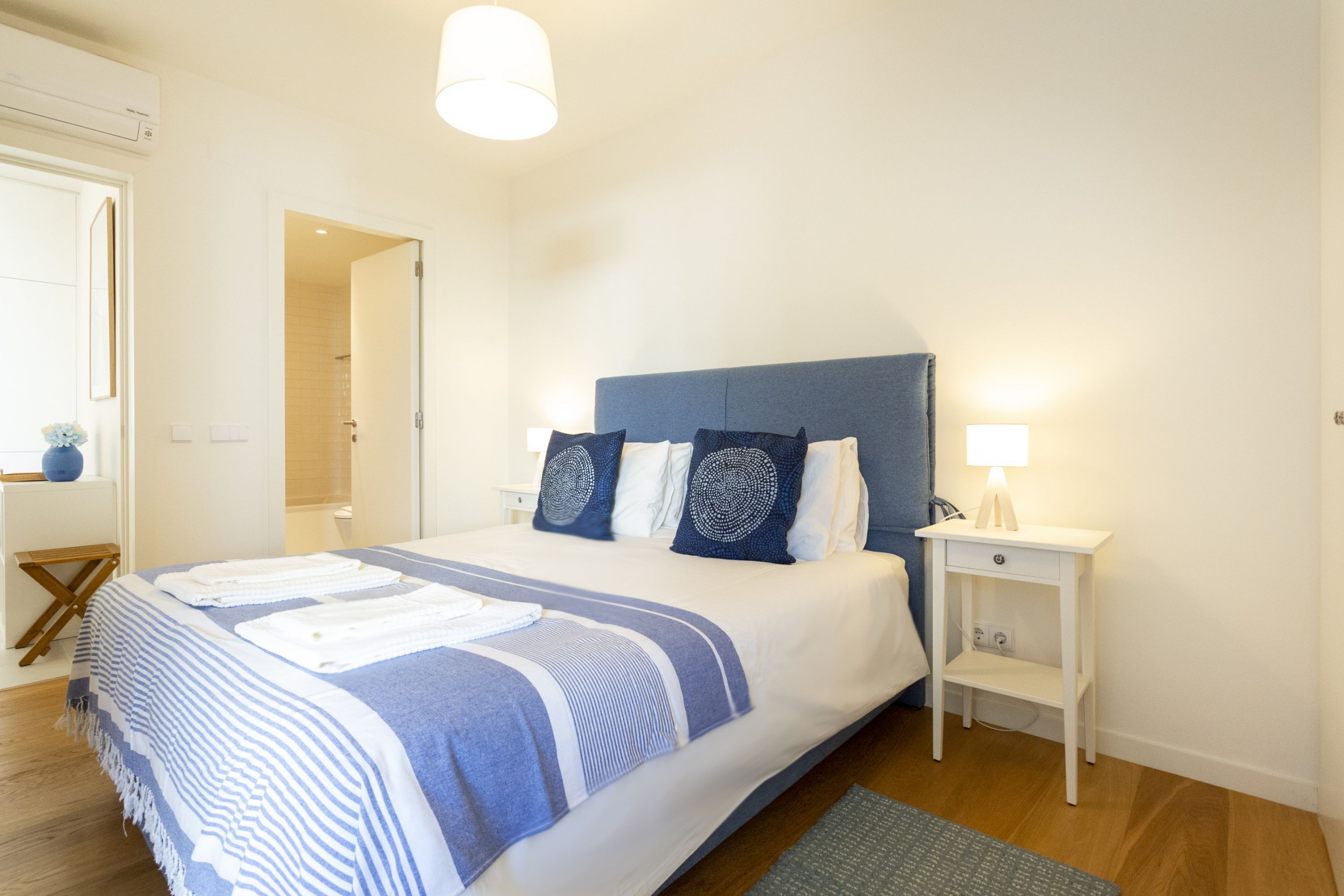 A neatly arranged bedroom with a bed, bedside table, and a lamp.