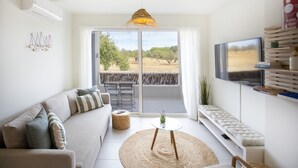 A modern living room with a sofa, a round table, and a TV. - Casas do Forte EF - Casa de Cabanas (Tavira)