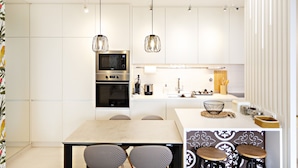 A modern kitchen with white cabinetry, stainless steel appliances, and pendant lighting.