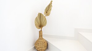 A corner of a room with a white wall and a white floor. There is a wicker vase with two leaves on top of it. - Special Cabanas in Tavira (Tavira)