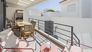 A balcony with a dining area, including a table and chairs, and a sofa with cushions. - Special Cabanas in Tavira (Tavira)