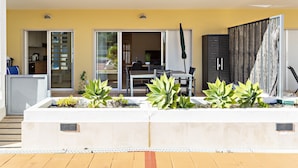 Un patio moderno al aire libre con zona de comedor, puertas correderas y un macetero con suculentas.