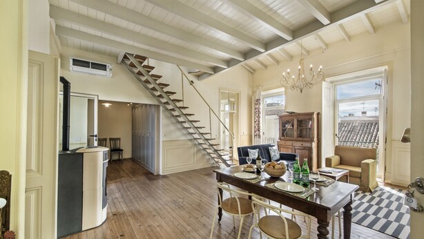 A spacious kitchen with a wooden staircase, a dining area with a table set for four, and a view of the city through a large window. - Casa do Jornal in Vila Real de Santo Ant nio (Vila Real Santo Antonio)