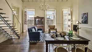 A spacious living area with a wooden staircase, a dining table set for four, and a view of the outside. - Casa do Jornal in Vila Real de Santo Ant nio (Vila Real Santo Antonio)