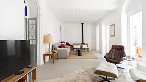 Un salon spacieux avec un grand téléviseur à écran plat, un canapé, un fauteuil en cuir marron et une table basse.