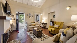 A spacious living room with a sofa, armchairs, a coffee table, and a TV mounted on the wall. - Casa Santo in Tavira (Tavira)