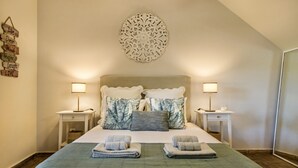 A neatly arranged bedroom with a bed, two bedside tables, a wall decoration, and a large mirror. - Casa Santo in Tavira (Tavira)