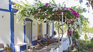 A covered outdoor seating area with stone walls, a bench, and a table. - Casa Santo in Tavira (Tavira)