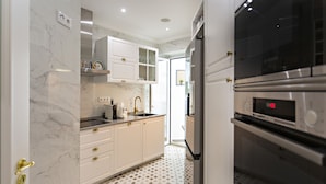 A modern kitchen with white cabinetry, a marble backsplash, and a patterned floor. - Blue Peacock in Faro (Faro)