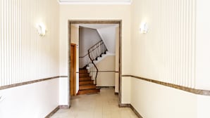A hallway with a wooden staircase leading to an upper floor. - Blue Peacock in Faro (Faro)