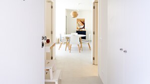 A modern, minimalist hallway leading to a dining area with white furniture and a large painting on the wall. - Casas do Forte CE in Tavira (Tavira)