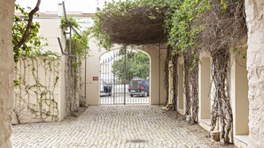 A cobblestone pathway leading to a gated entrance with a wrought iron gate. - CV BC - Convento das Bernardas (Tavira)