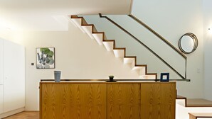 A modern kitchen with a wooden island, a staircase, and a wall-mounted mirror. - CV P- Convento das Bernardas (Tavira)