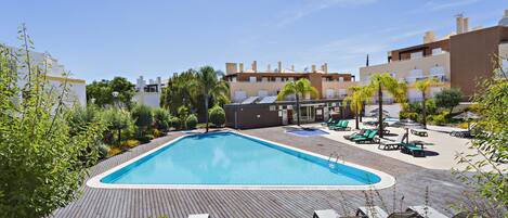 A swimming pool surrounded by lounge chairs and a wooden deck.