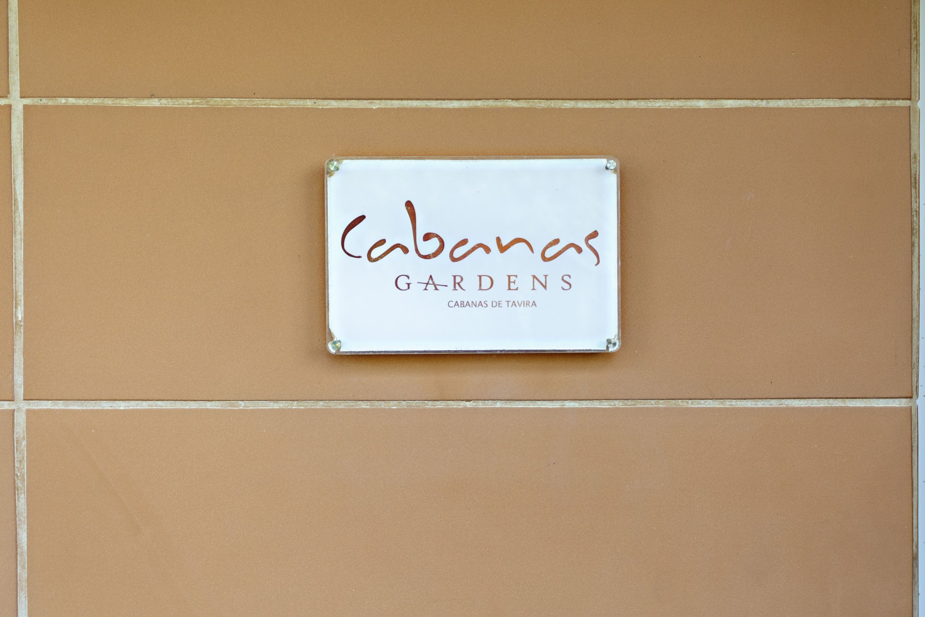A sign with the text "Cabanas GARDENS" on a tiled wall.