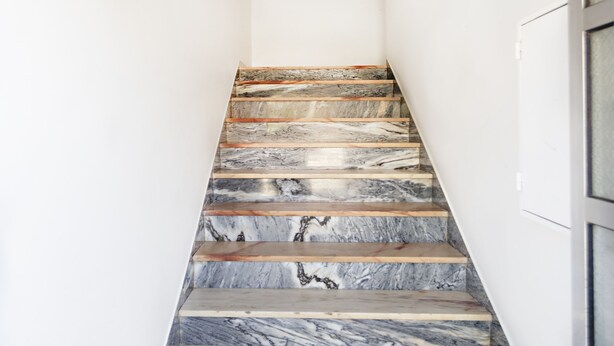 A staircase with marble steps and wooden handrails.