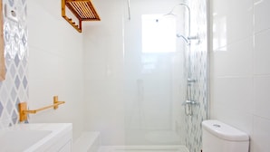 Un baño moderno con ducha, inodoro y tocador con cajones.