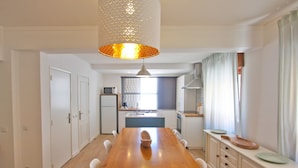 Una cocina moderna con armarios blancos, una mesa de comedor de madera y una lámpara colgante.