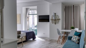 Ein modernes Wohnzimmer mit einer Couch, einem Esstisch und einem an der Wand befestigten Fernseher.