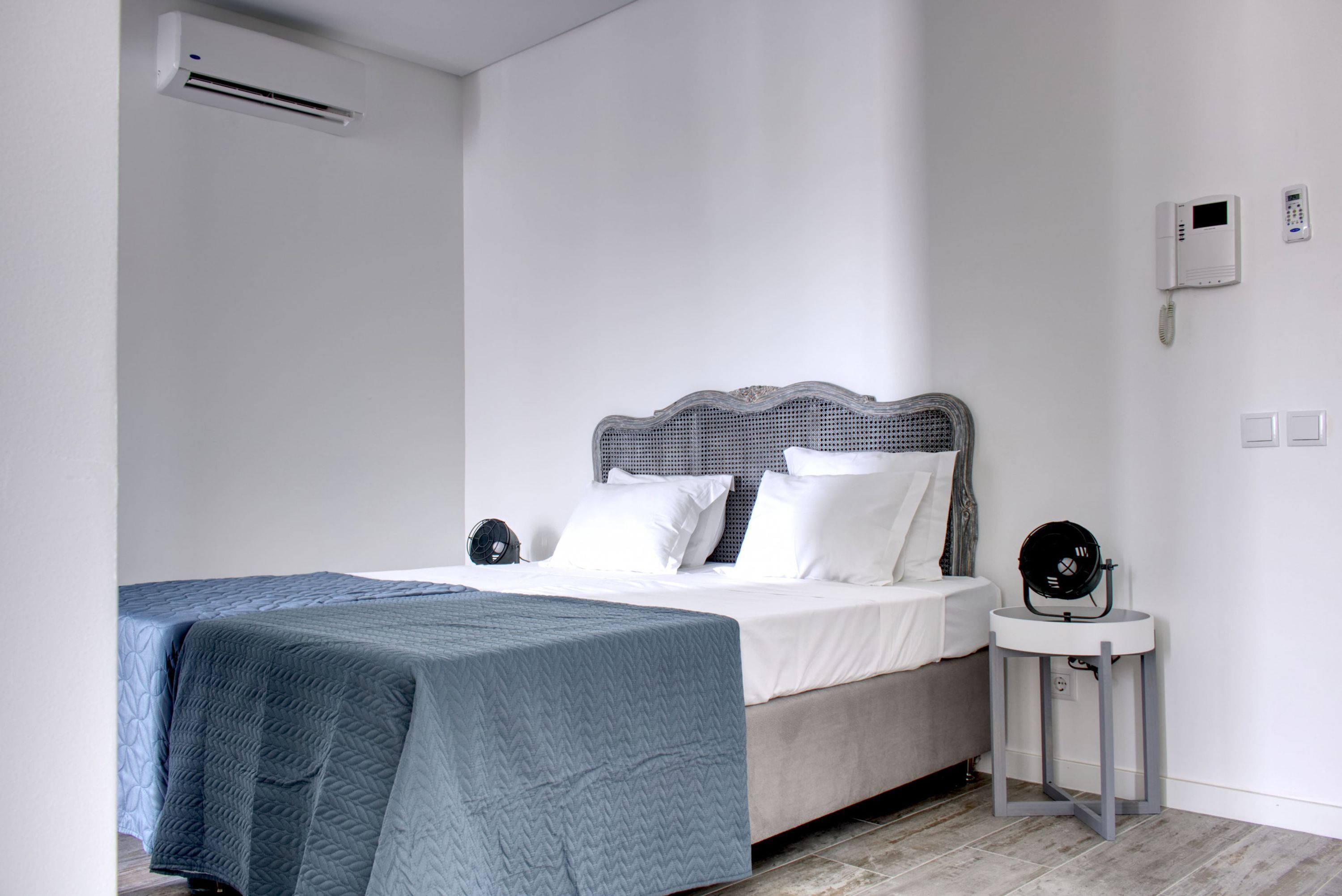 Une chambre à coucher avec un lit, une table de chevet et un téléphone fixé au mur.