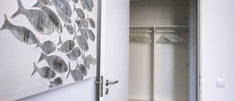 Une pièce avec une porte blanche, une décoration murale représentant des poissons et un placard partiellement visible, dans lequel on peut apercevoir des vêtements suspendus.