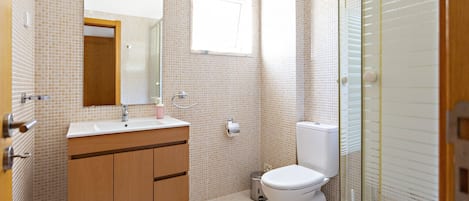 A bathroom with a sink, mirror, toilet, and shower.