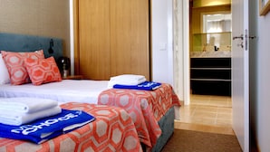 A hotel room with two beds, a wooden wardrobe, and a bathroom visible through an open door. - Formosa Bay - HB in Tavira (Tavira)