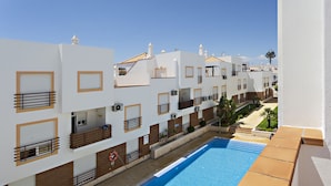 A row of white buildings with balconies, a swimming pool, and a clear sky. - Cabanas Terrace in Tavira (Tavira)
