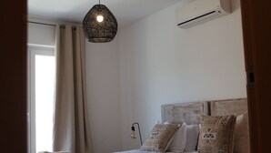 Een slaapkamer met een bed, een hanglamp, een airconditioning en een raam met gordijnen.