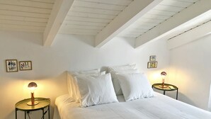 A bedroom with a bed, two bedside tables with lamps, white bedding, and framed pictures on the walls. - Casa Dona Ana in Tavira (Tavira)
