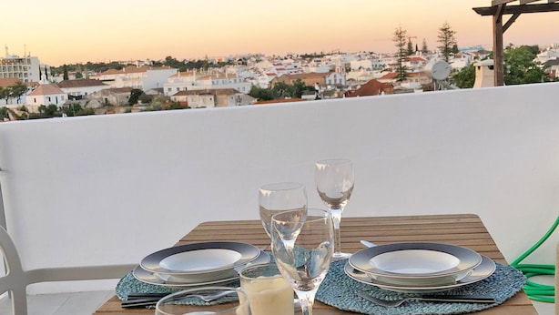 A table set for two with plates, cutlery, and glasses, overlooking a cityscape. - Casa Dona Ana in Tavira (Tavira)