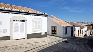 A cobblestone street with white buildings featuring tiled roofs and traditional doors. - Casa Dona Ana in Tavira (Tavira)