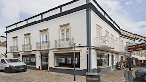 Ein weißes Gebäude mit Balkonen und einem Schild, das 'Mercado da Ribeira' und 'Jardim do Correio' ausweist.