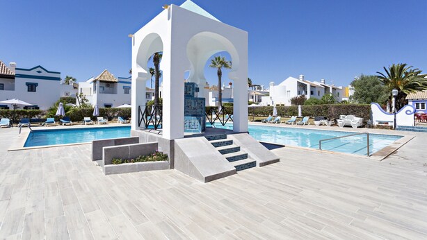 A swimming pool with a white gazebo structure, lounge chairs, and palm trees. - QV 4 - Villa Rustique - Quinta Velha (Tavira)