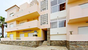 A multi-story building with balconies, a stone base, and a flat roof. - Fleming Apartment in Tavira (Tavira)