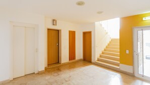 A spacious hallway with a marble floor, wooden doors, and a staircase leading to a balcony. - Fleming Apartment in Tavira (Tavira)