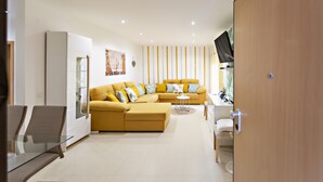 A modern living room with a yellow sofa, a glass coffee table, and a white cabinet. - Fleming Apartment in Tavira (Tavira)