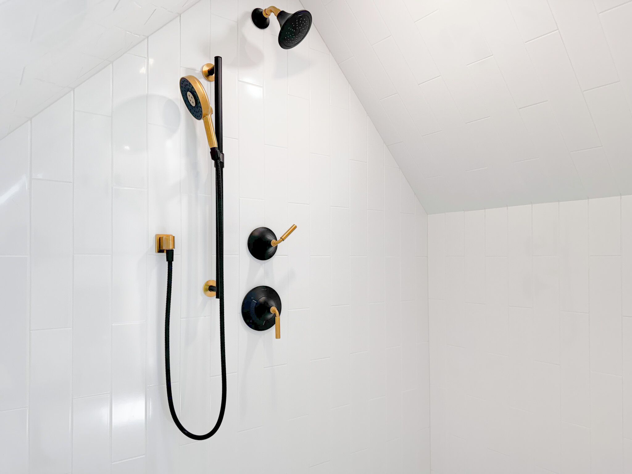 A shower with a handheld showerhead, a handheld massage nozzle, and a wall-mounted showerhead.